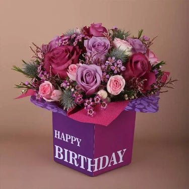 Many Happy Returns Of The Day, Birthday Flowers Arrangement, Dark Pink Roses, Purple Roses, Eryngium Flowers, Pink Spray Roses, Purple Wax Flowers, Pink Limonium Leaves, Square Glass Vase